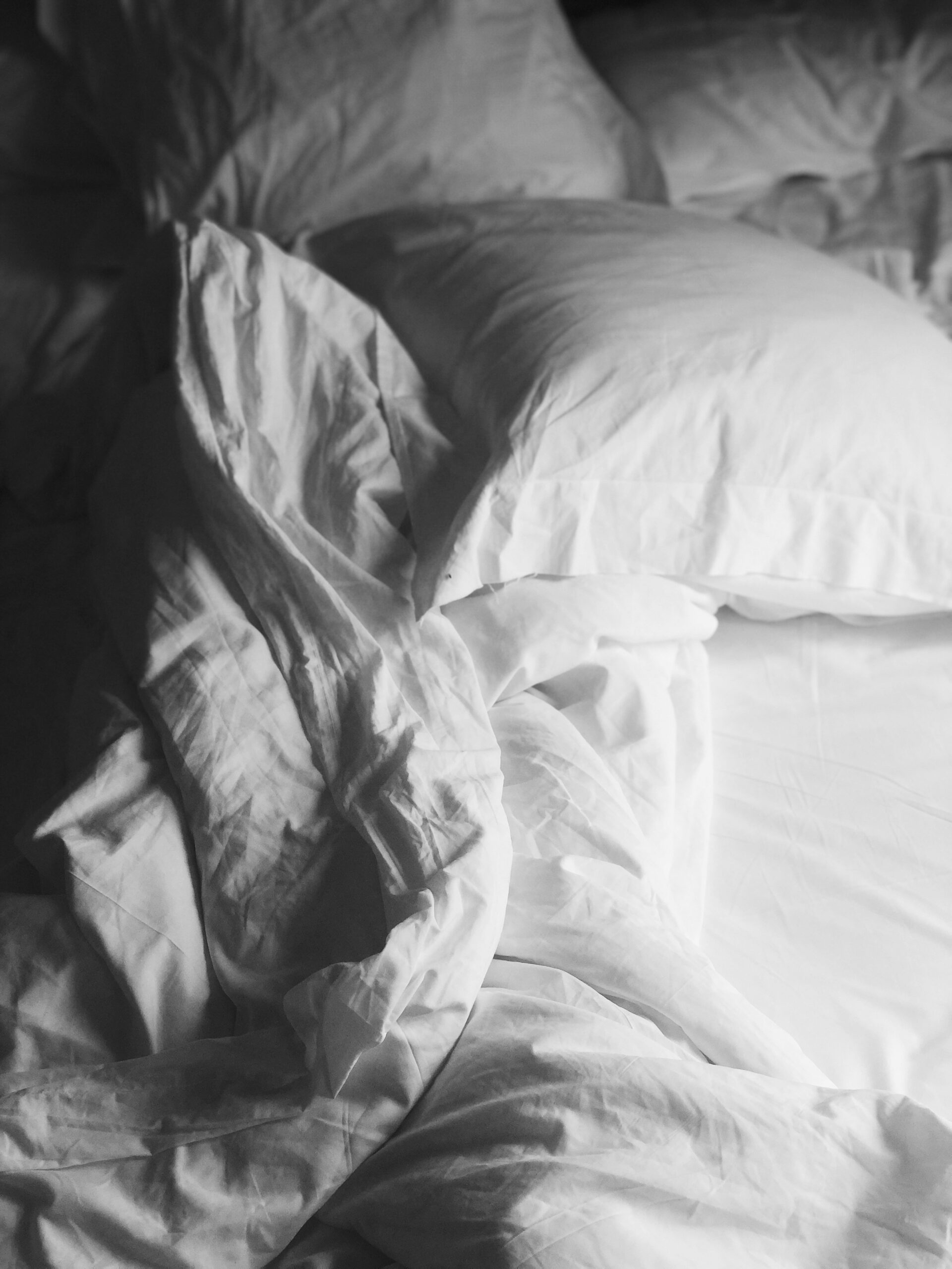 Rumpled white bed sheets and pillows.